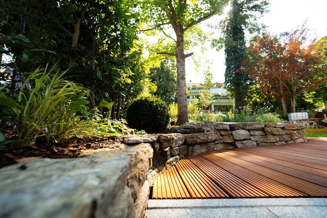 Modern trädgård med låg natursten-mur som ramar in en träaltan