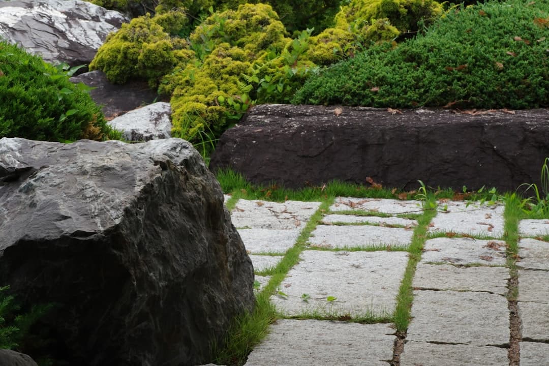 Granithällar med gräs i fogarna intill mossbädd och naturstensblock