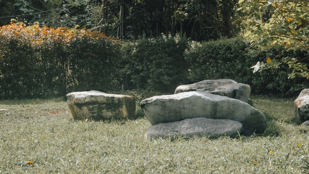 Tre stora naturstensblock placerade på en gräsmatta som rumsbildare i en trädgård